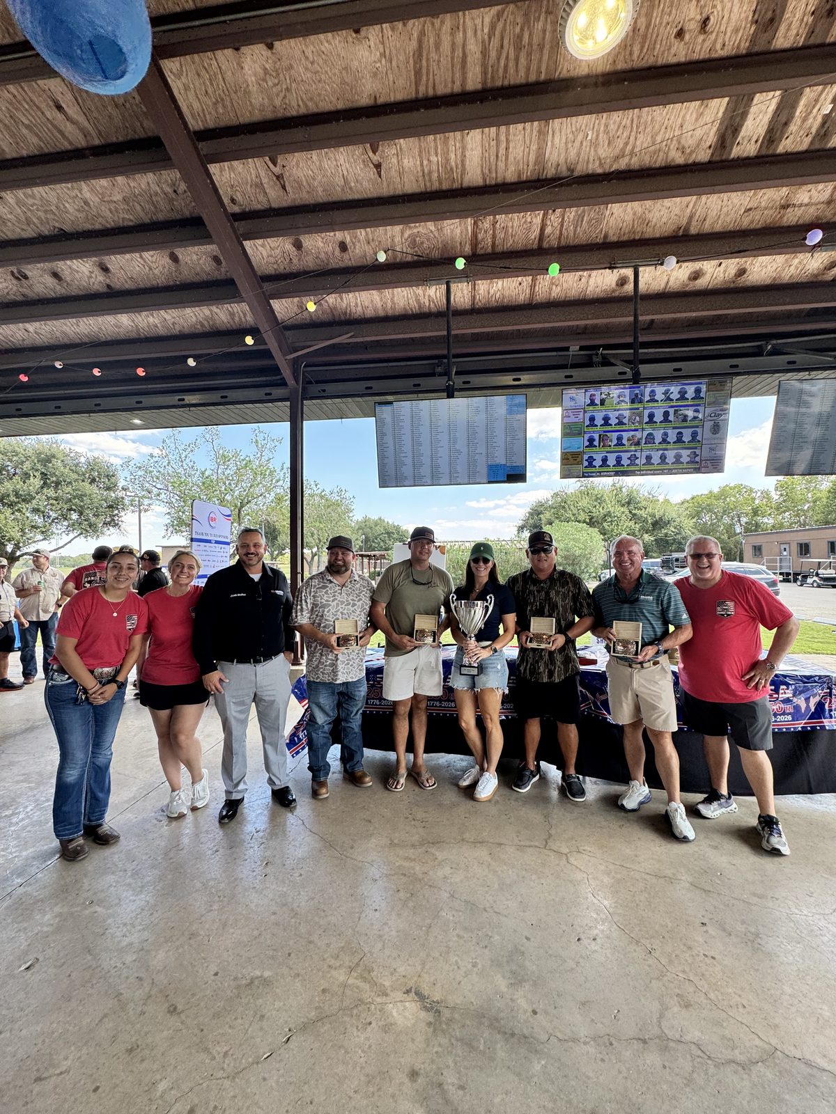 Group holding a trophy and award boxes at the 5th Annual IBR Clay Shoot.