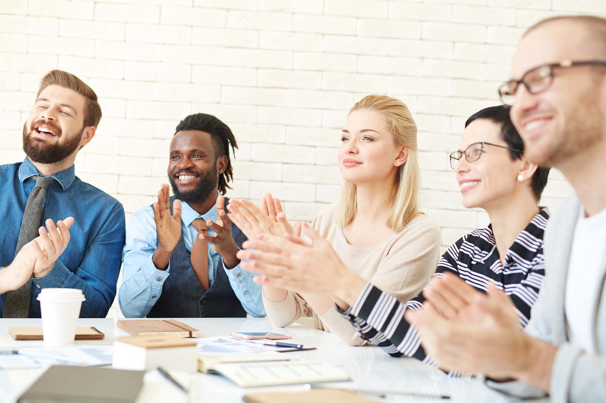 Five colleagues clapping at something offscreen