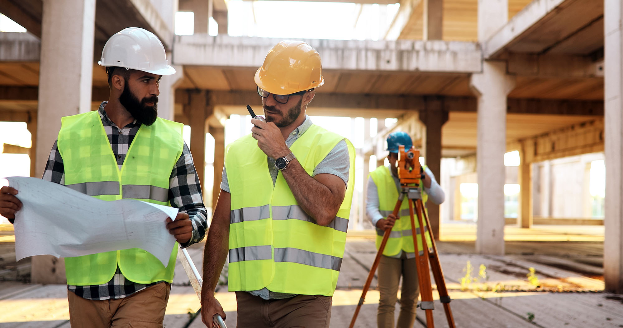 Three workers in hi-vis vests and hard hats